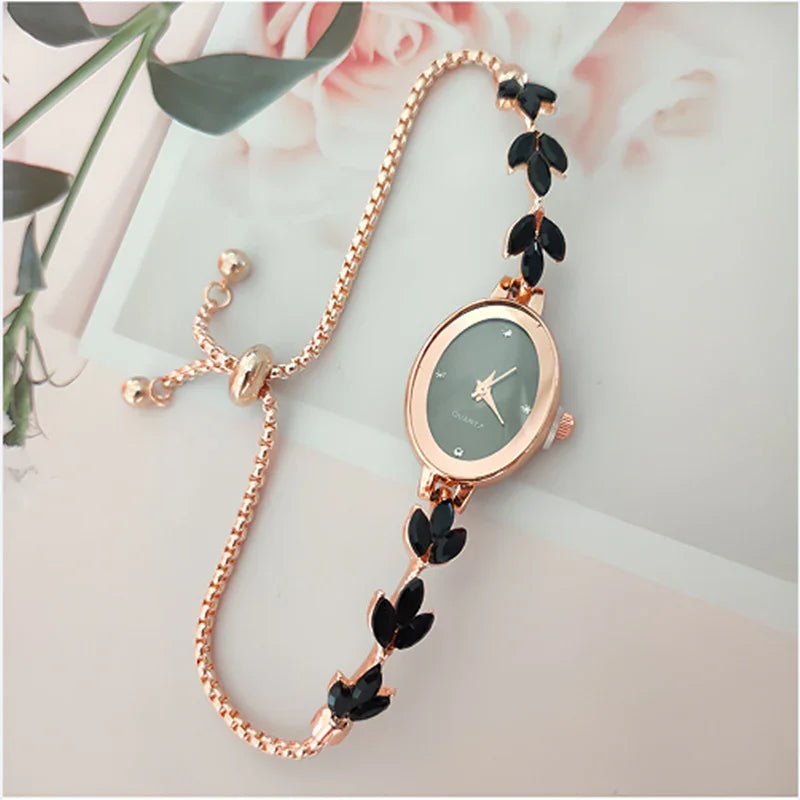 Elegant rose gold bracelet watch with black leaf-shaped accents on adjustable chain strap