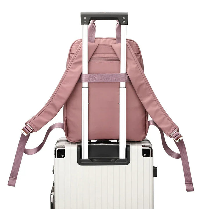 Pink backpack attached to the handle of white hard-shell rolling suitcase on white background