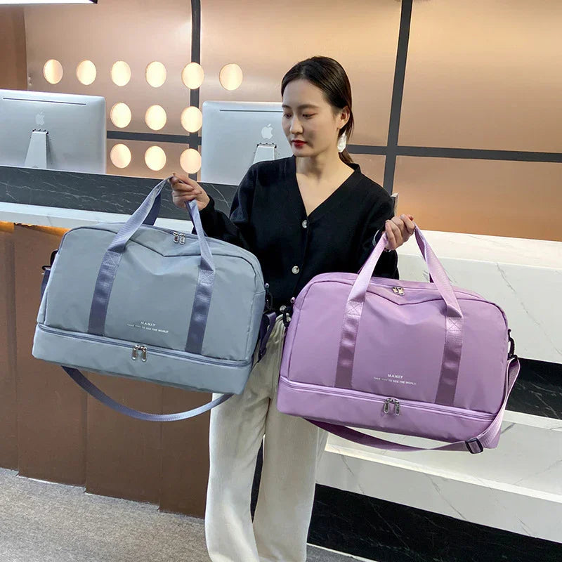 Woman holding gray and purple travel duffel bags in modern office setting
