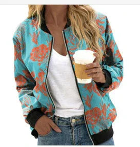 Woman wearing teal floral bomber jacket holding a coffee cup with white top and light wash jeans