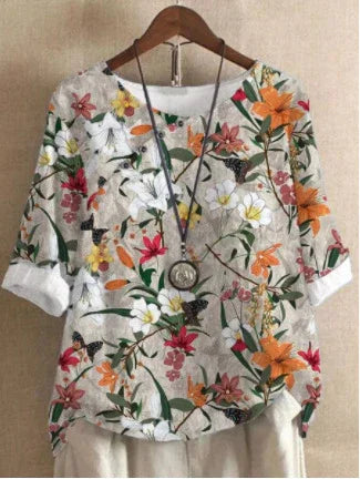 Floral print linen blouse with orange, pink, and white flowers on a beige background, paired with a round pendant necklace