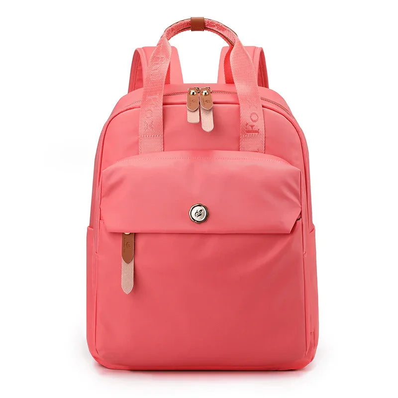 Modern coral pink backpack with front pocket, dual zippers, and padded straps on white background