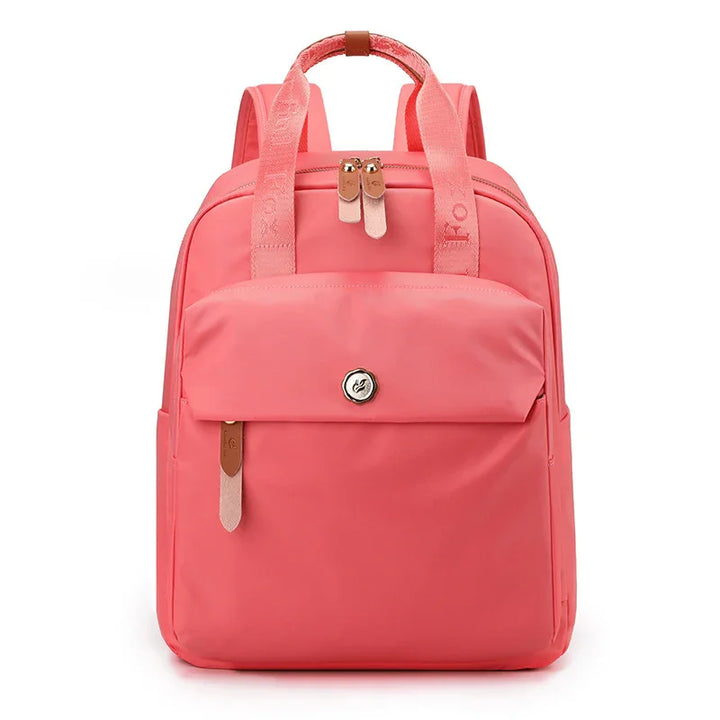 Modern coral pink backpack with front pocket, dual zippers, and padded straps on white background