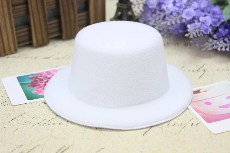 White mini felt top hat on vintage paper with floral postcards and purple flowers background