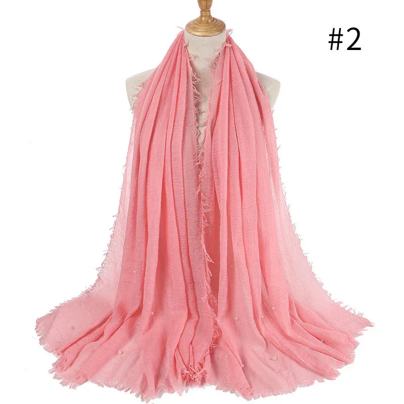 Soft pink fringed scarf with subtle pearl embellishments displayed on mannequin
