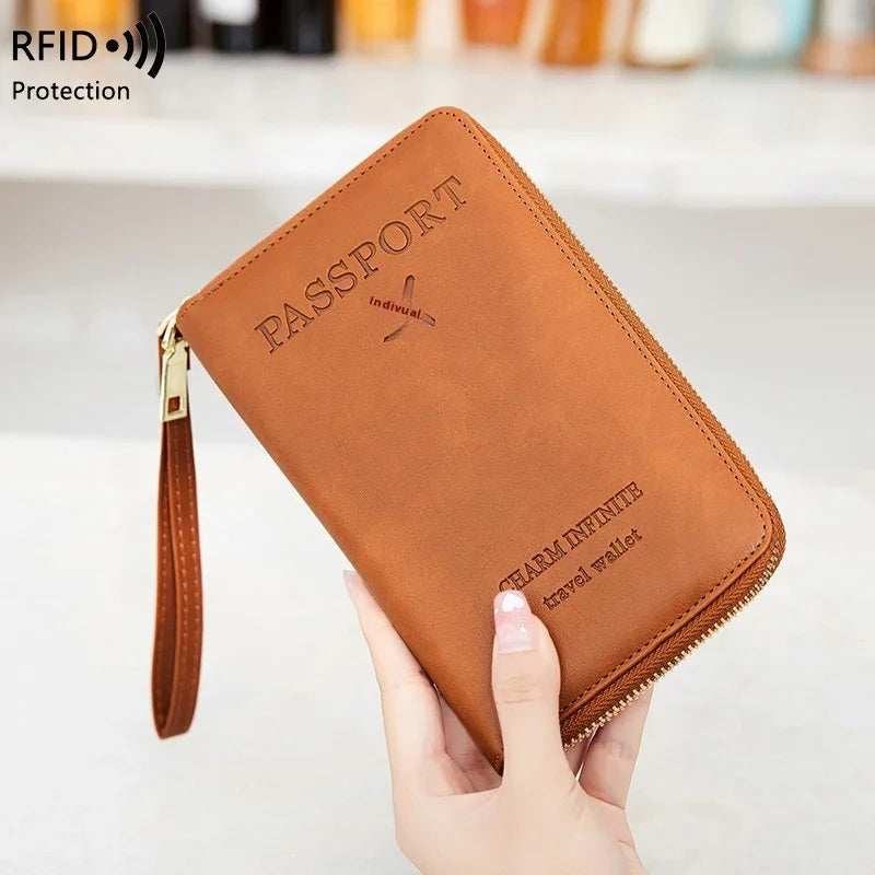 Hand holding brown leather RFID protection travel wallet with zipper and wrist strap