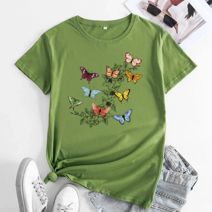 Green t-shirt with colorful butterfly print and floral design, paired with denim shorts and white sneakers