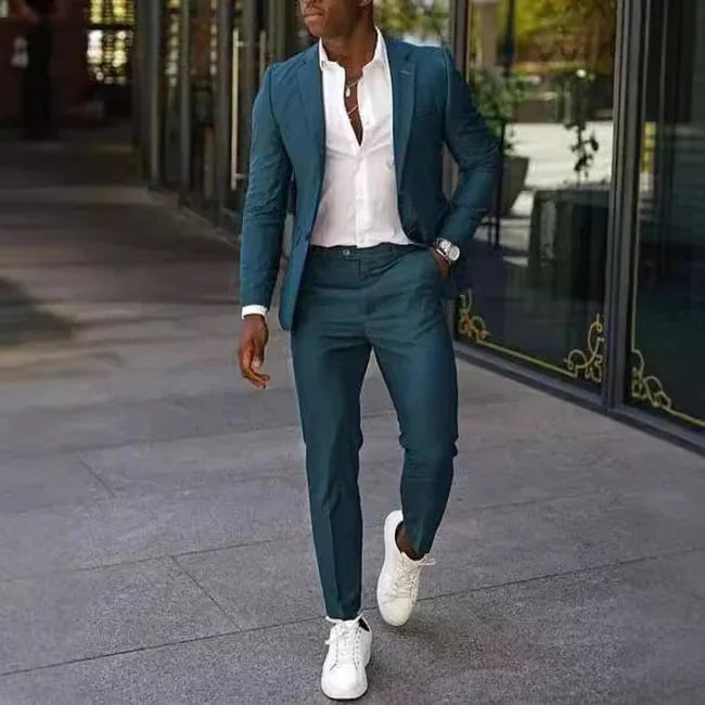 Stylish man walking outdoors in a slim-fit blue suit paired with a white shirt and white sneakers