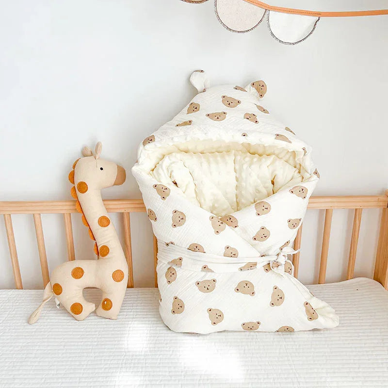 Cozy baby swaddle blanket with bear print next to soft giraffe plush toy on wooden crib