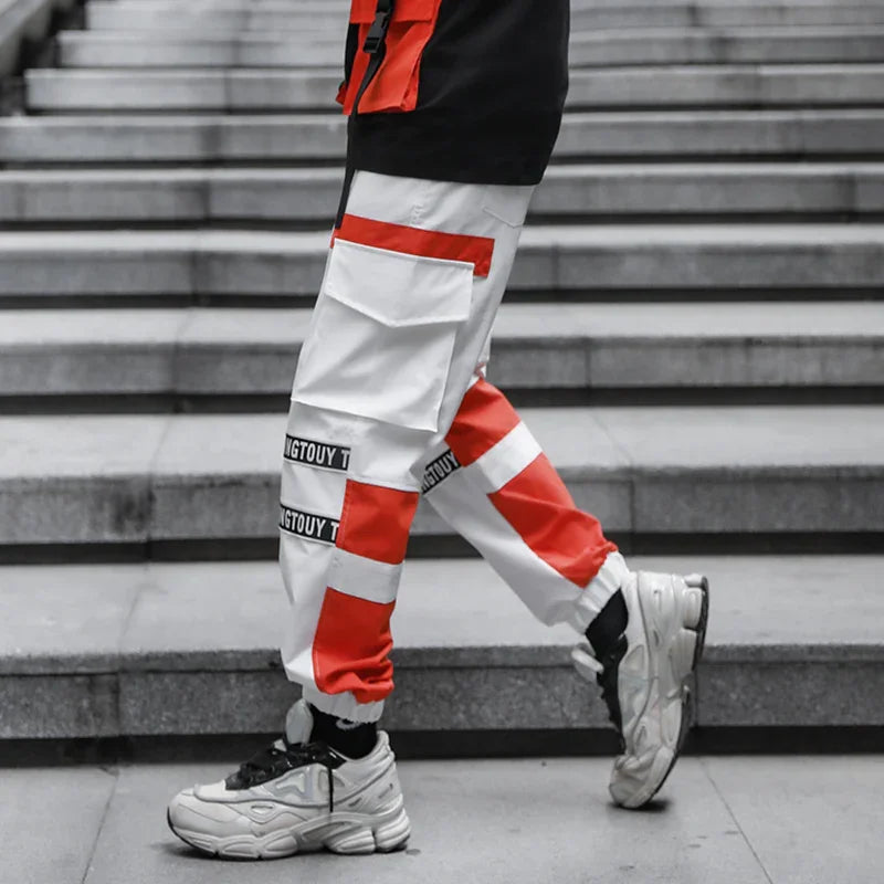 Person wearing white and red cargo pants with black text and white sneakers walking down concrete stairs