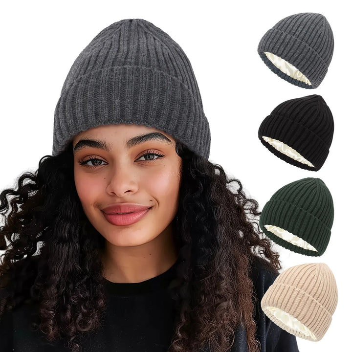 Curly haired woman wearing a gray knit beanie with four additional knit beanies in gray, black, green, and beige shown