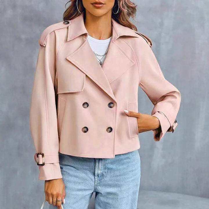 Woman wearing a light pink double-breasted cropped trench coat with casual light blue jeans