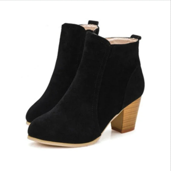 Pair of black suede ankle boots with block wooden heels on white background
