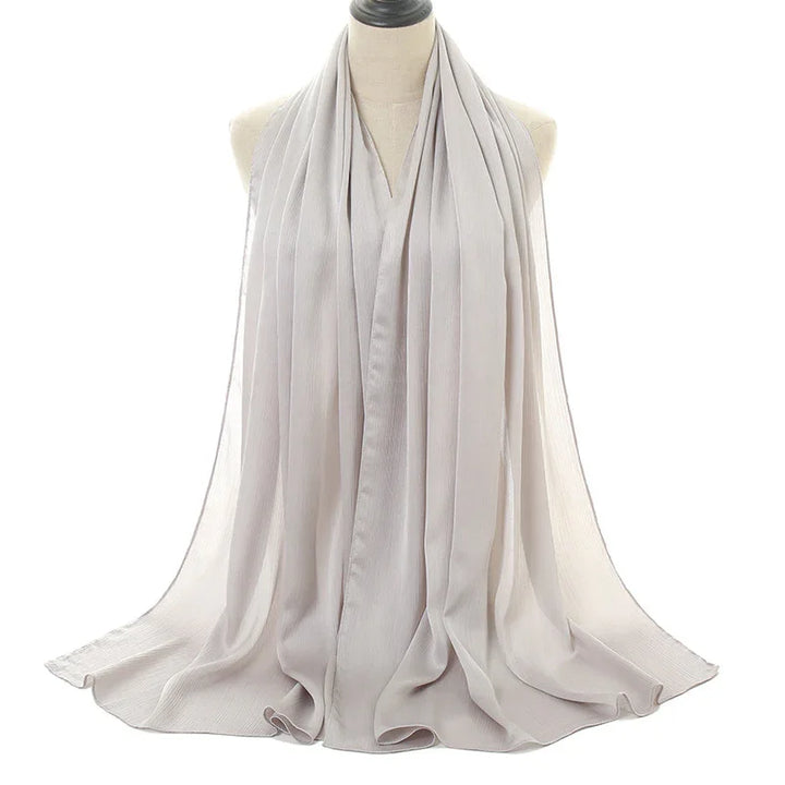 Light gray pleated chiffon scarf displayed on mannequin with flowing texture