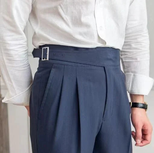 close-up of man wearing high-waisted navy pleated trousers with belt and white long-sleeve shirt