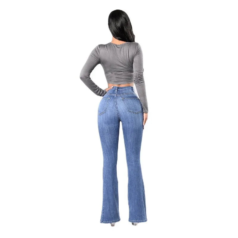 Woman wearing grey long-sleeve crop top and high-waisted blue flare jeans standing back view