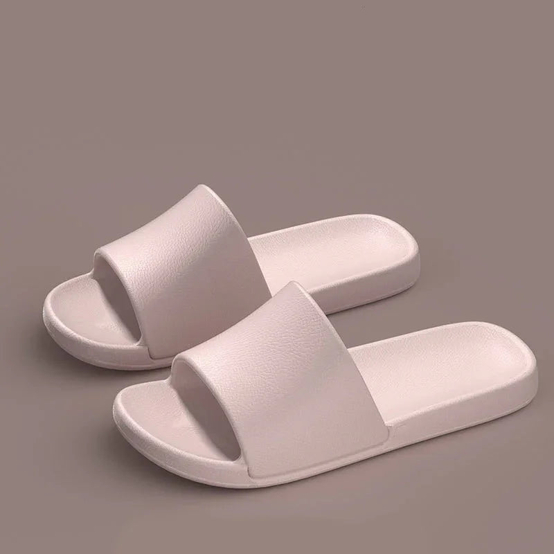 Minimalist light pink slide sandals with wide strap and textured footbed on neutral background