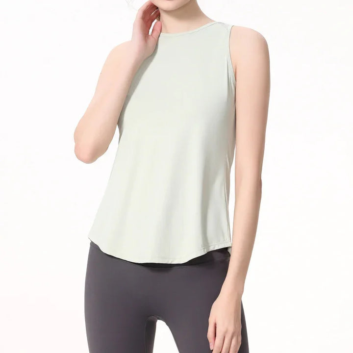 Woman wearing light gray sleeveless yoga tank top and dark leggings on white background