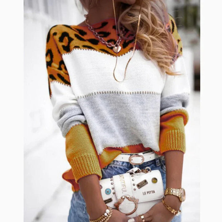 Woman wearing color block sweater with leopard print, light blue jeans, and white belt bag