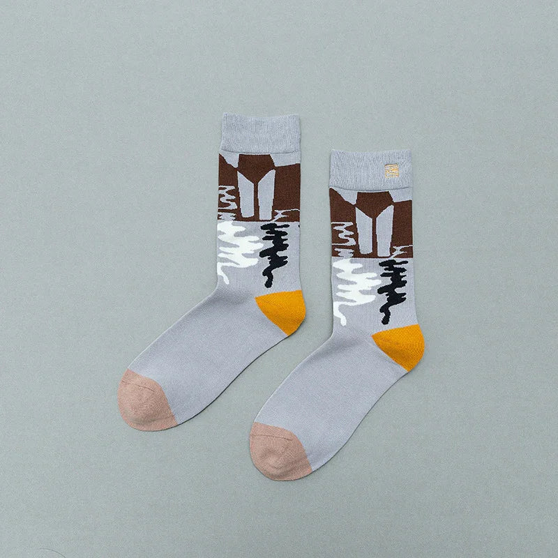 Pair of gray crew socks with abstract brown, white, black pattern and orange heel on light gray background