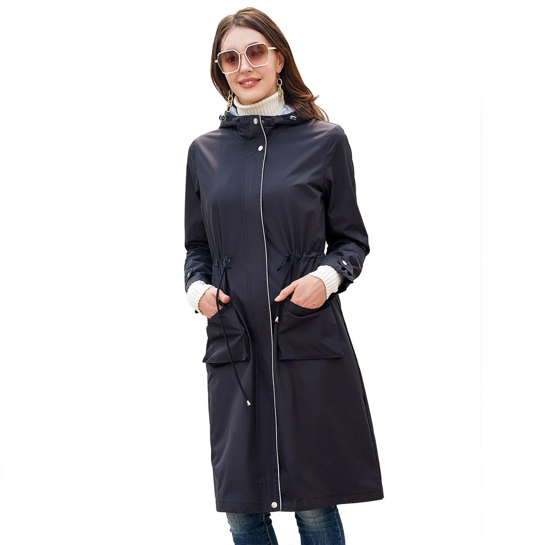 woman wearing a long navy blue hooded raincoat with large front pockets and drawstring waist