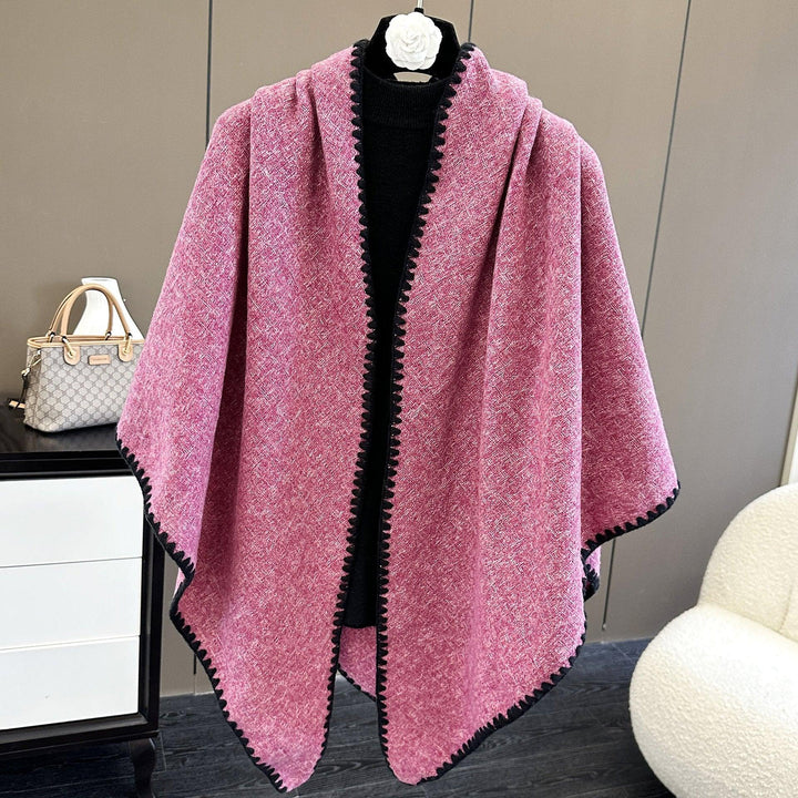 Pink textured wool cape with black trim displayed on a mannequin in a modern interior