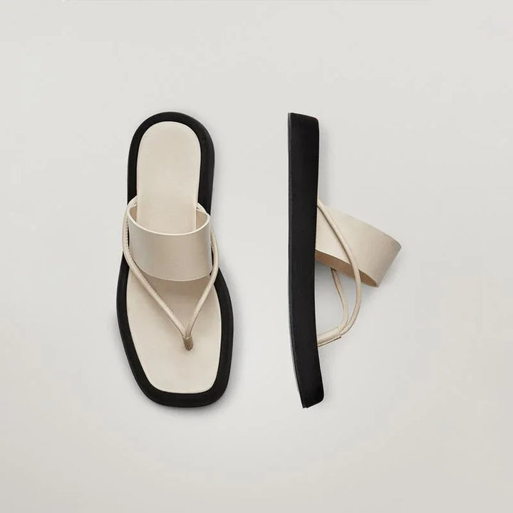 Minimalist beige and black platform thong sandals with wide straps on neutral background