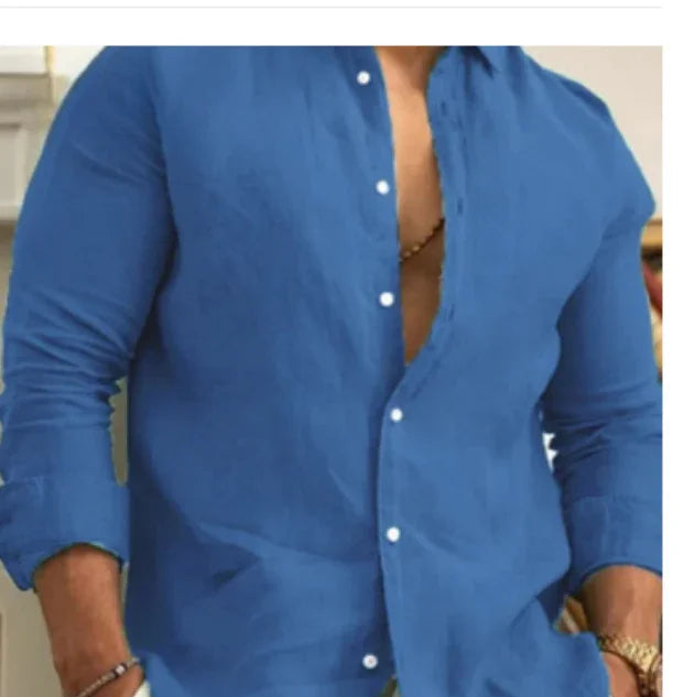 Man wearing an unbuttoned blue long-sleeve shirt with rolled cuffs and a visible necklace