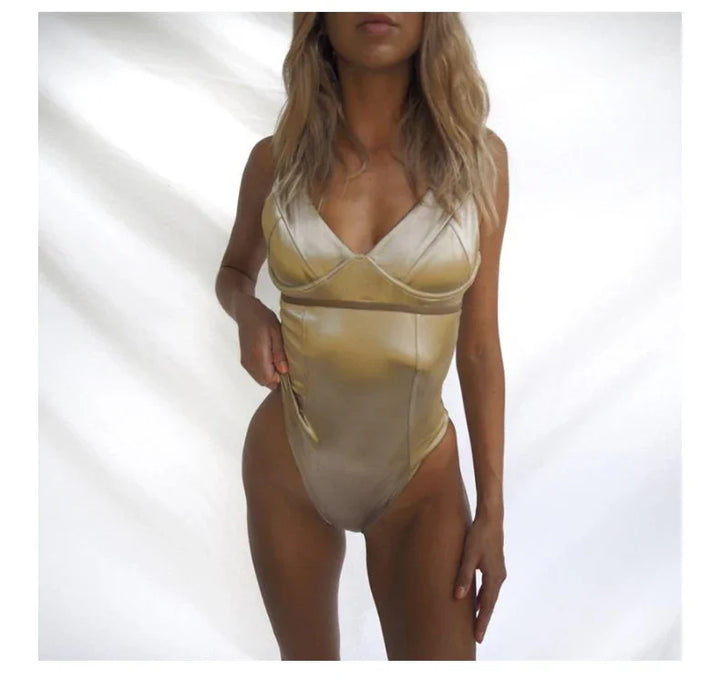 Woman wearing shiny gold satin one-piece swimsuit with deep V neckline against white background