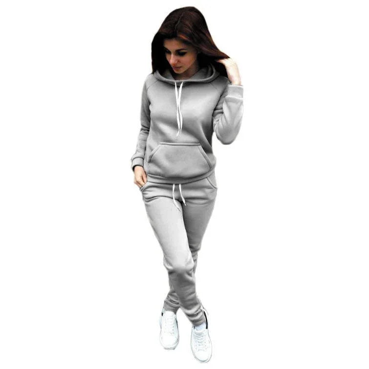 Woman wearing light gray hoodie and sweatpants with white sneakers on white background