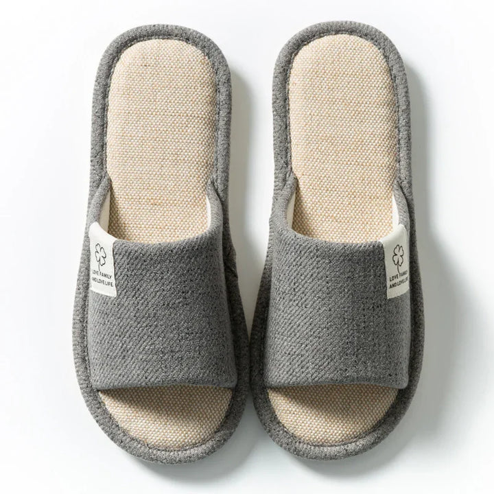 Pair of gray open-toe indoor slippers with beige textured insoles and fabric tags on a white background