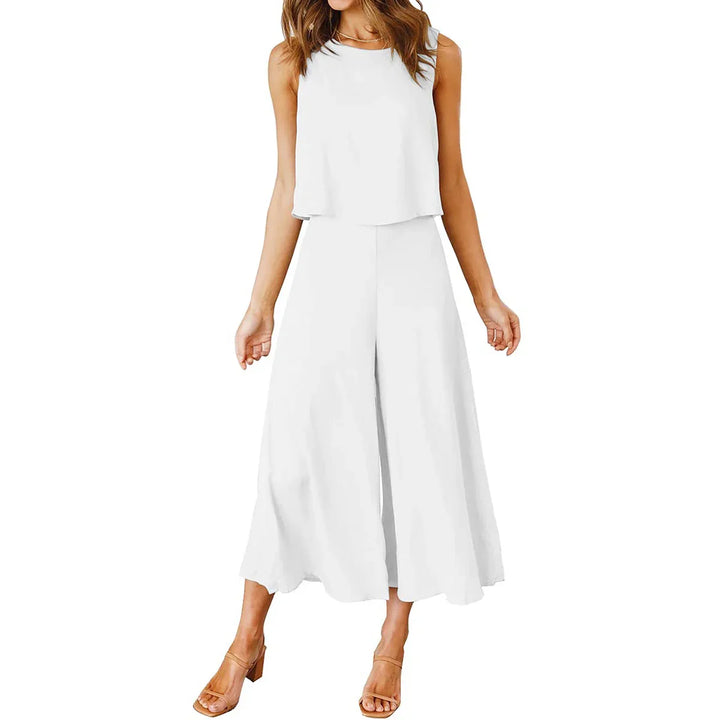 Woman wearing white sleeveless cropped top and wide-leg culotte pants with tan open-toe heels