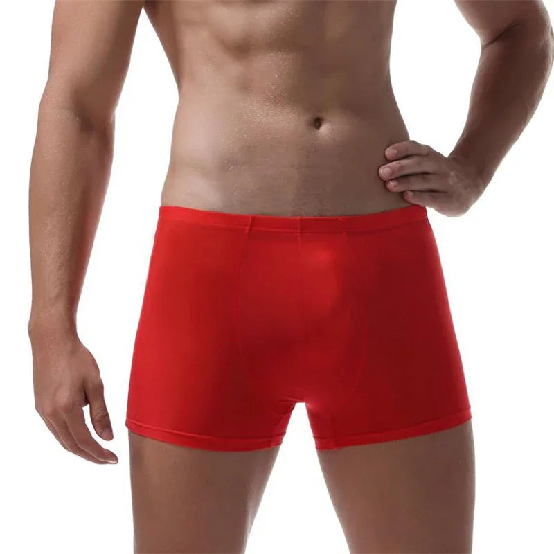 Male model wearing red boxer briefs standing with hand on hip, white background
