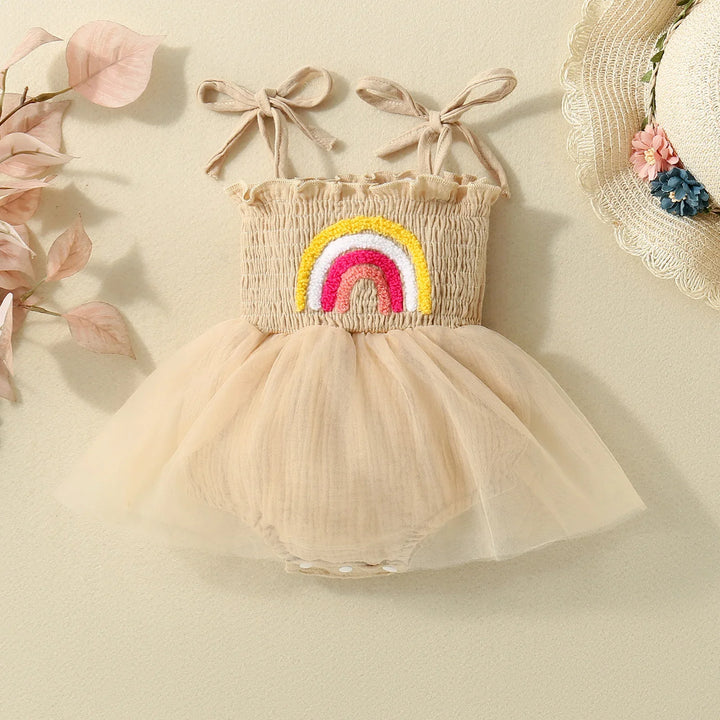 Beige baby dress with rainbow embroidery, tulle skirt, bow shoulder straps, and floral straw hat