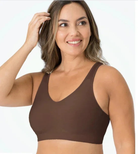 Smiling woman wearing a brown seamless bra top against a white background