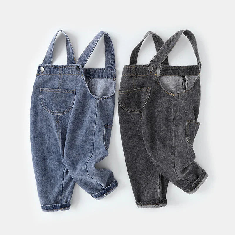 Two pairs of children's denim overalls in blue and black with front pockets and adjustable straps
