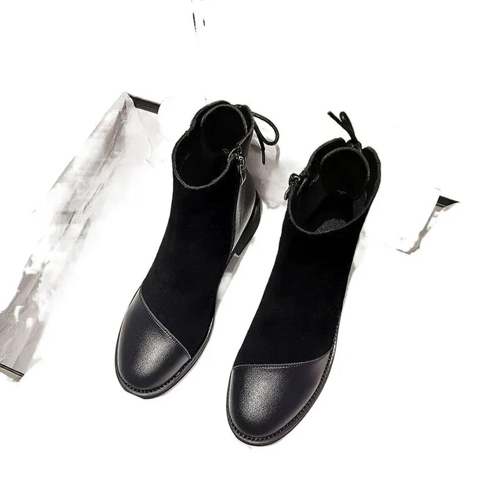 Black ankle boots with leather toe caps and side zippers on white background