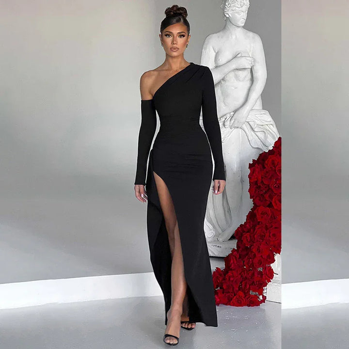 Woman in elegant black one-shoulder dress with high slit, posing beside white statue and red roses