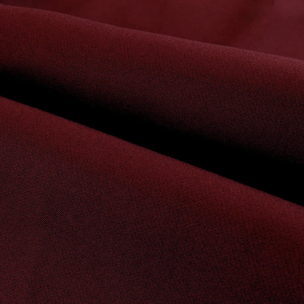 Close-up of dark burgundy fabric with folded texture, highlighting fine weave and smooth surface