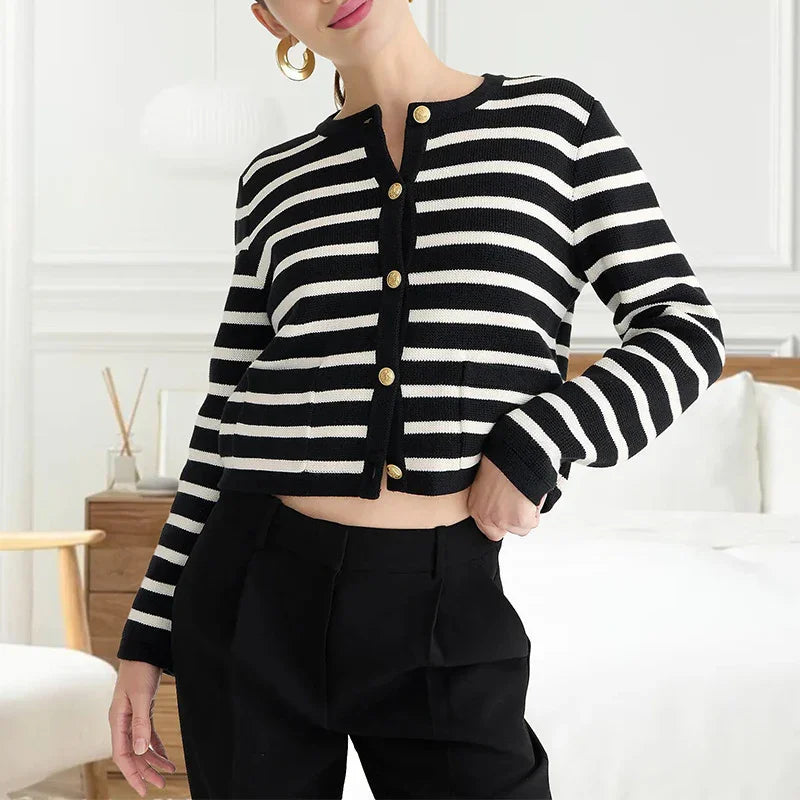 Woman wearing black and white striped button-up cardigan with gold buttons and black pants
