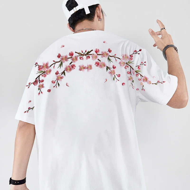 Man wearing white T-shirt with pink cherry blossom floral design on back and arms