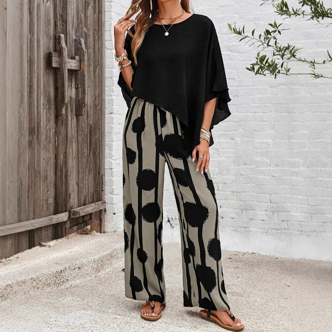 Woman wearing black asymmetric top and wide-leg beige pants with black circle and stripe pattern outdoors
