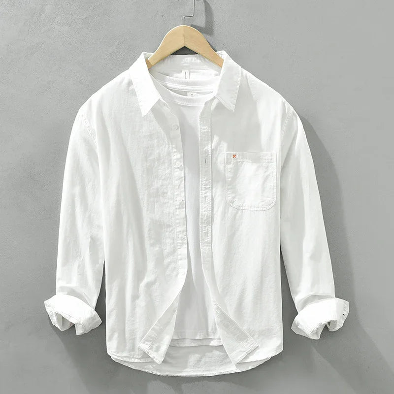 White casual button-up shirt with chest pocket over white t-shirt on wooden hanger