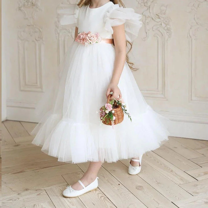 Girl wearing white tulle dress with floral waist belt holding small wicker basket with flowers