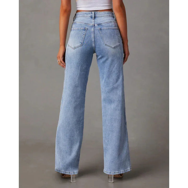Back view of woman wearing light blue high-waisted wide-leg jeans and white crop top