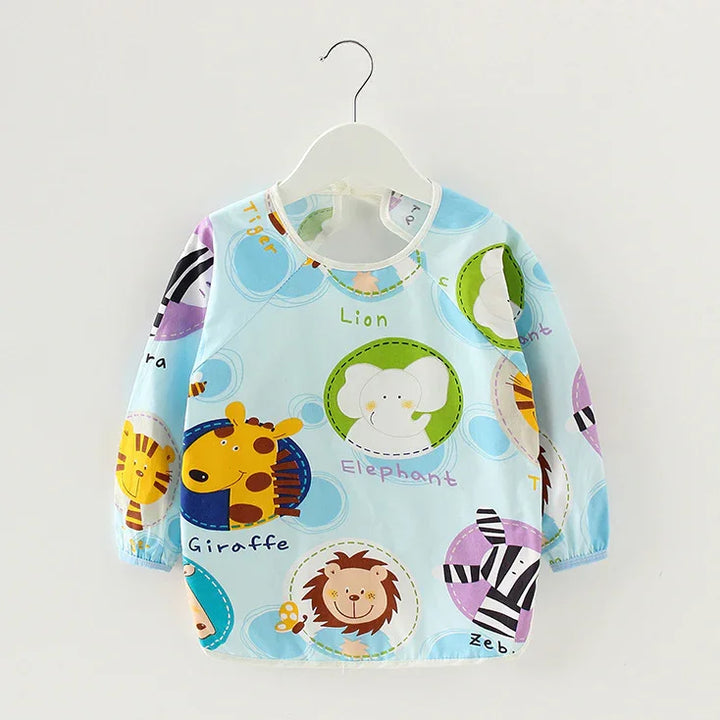 Light blue children's smock with colorful cartoon animals including giraffe, lion, elephant, zebra, and tiger.