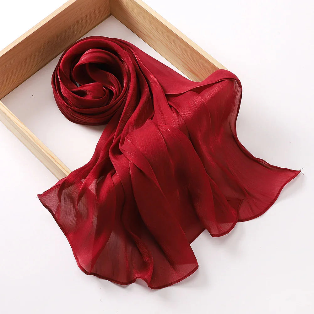 Elegant sheer red chiffon scarf rolled inside a wooden frame on white background