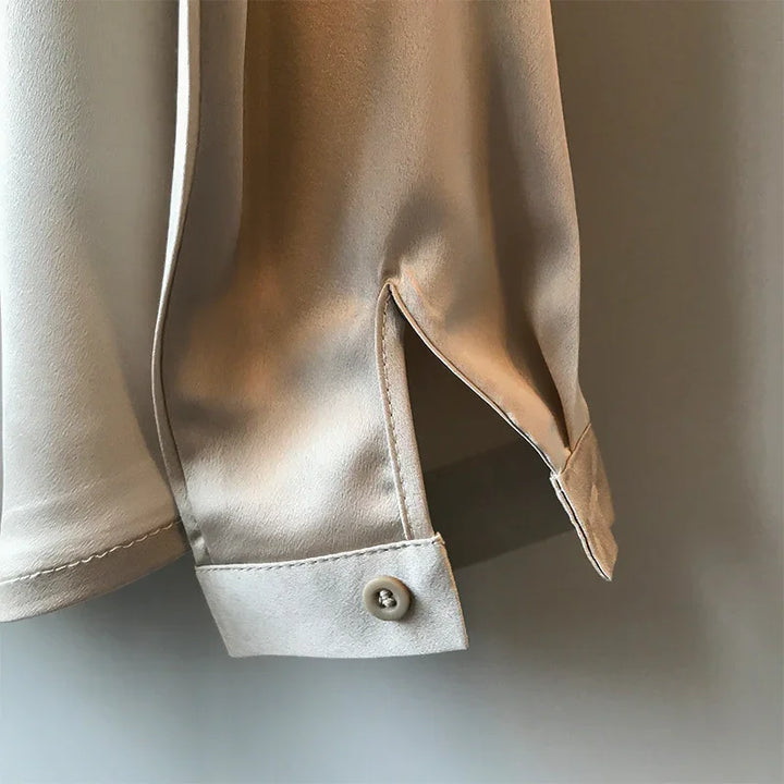 Close-up of beige shirt cuff with button and side slit detail on smooth fabric