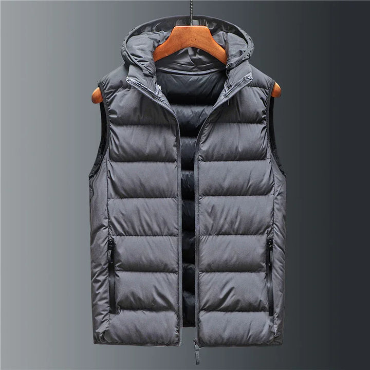 Black sleeveless padded vest with hood hanging on wooden hanger against gray gradient background
