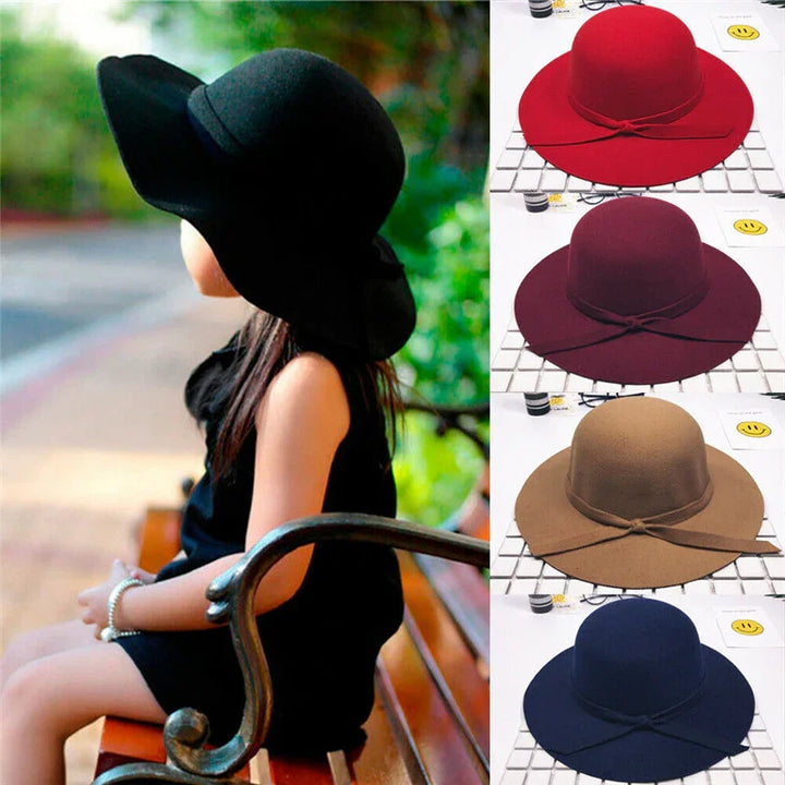 Girl wearing black wide-brimmed hat sitting on wooden park bench with four color options of similar hats